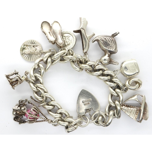 28 - Heavy gauge 925 silver charm bracelet with hallmarked padlock clasp and eleven charms, bracelet L: 2... 