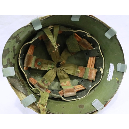 2185 - A Spanish M42 steel helmet with leather and canvas liner, with a German M35 camouflage helmet cover.... 