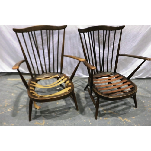 2074 - A pair of Ercol elm stick back armchairs with loose cushions, webbing requires attention, some wear ... 