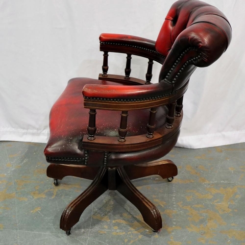 2122 - A 20th century Chesterfield style swivel desk chair, upholstered in ox blood leather on a five spoke... 