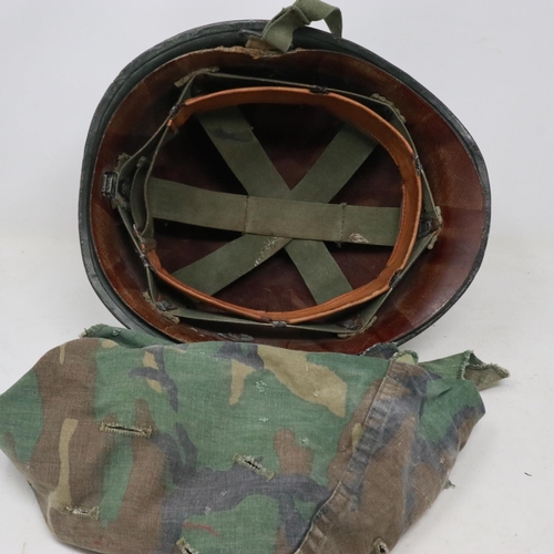 2131 - An American M-1 helmet and liner, later painted with Vietnam War US Airborne memorial, with camoufla... 