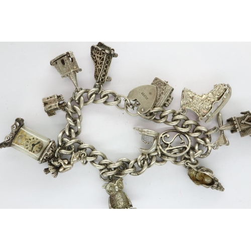 34 - Silver charm bracelet with thirteen charms, padlock clasp and safety chain, L: 18 cm, 63g. UK P&P Gr... 