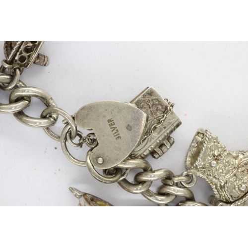 34 - Silver charm bracelet with thirteen charms, padlock clasp and safety chain, L: 18 cm, 63g. UK P&P Gr... 