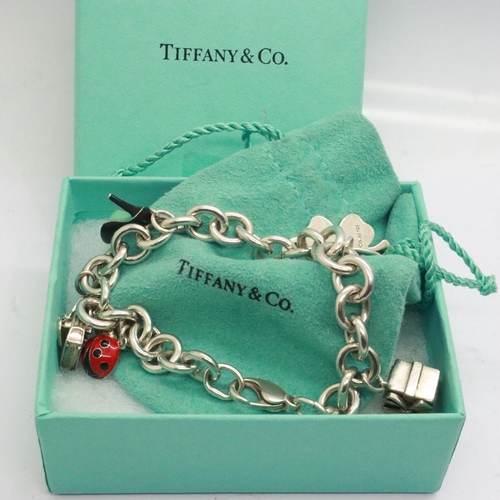 53 - 925 silver charm bracelet marked for Tiffany & Co with seven charms, receipt of £141 for the enamell... 