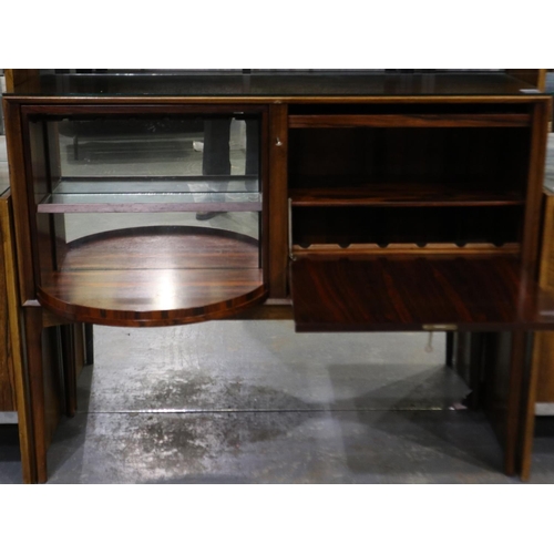 2105 - A mid 20th century rosewood drinks cabinet having a rotating bottle cupboard with mirrored back and ... 