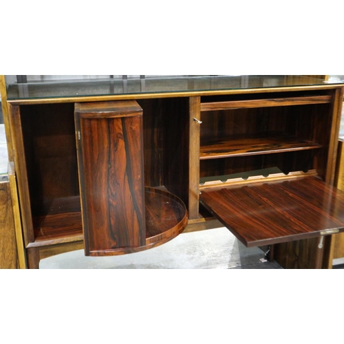 2105 - A mid 20th century rosewood drinks cabinet having a rotating bottle cupboard with mirrored back and ... 