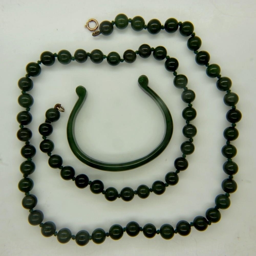 28 - A single strand beaded necklace of polished jade, having a 9ct gold clasp, open L: 64 cm, with a pol... 