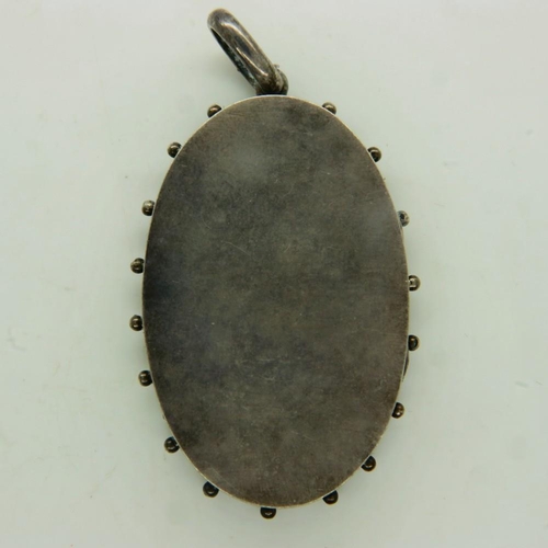 61 - A large Victorian silver oval locket, floral decorated in relief, unmarked, drop L: 60 mm (including... 