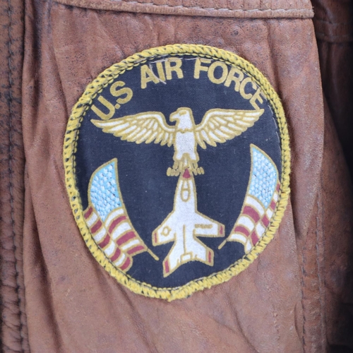 2161 - An American brown leather flying jacket, with sewn patches to the USAF, approximate size M. UK P&P G... 