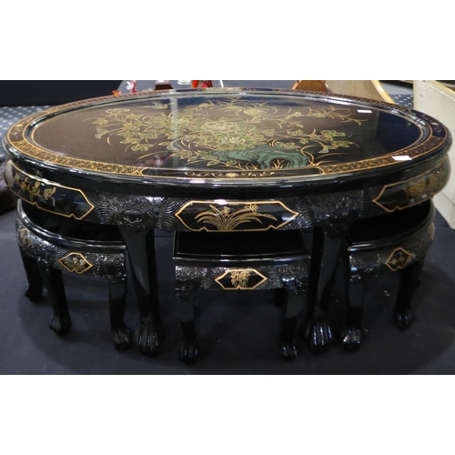 2058 - Contemporary black lacquered oval centre table, having six smaller tables beneath and protective gla... 