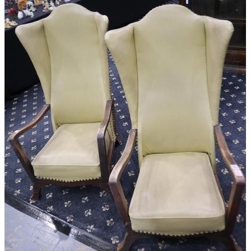 2063 - A pair of early 20th century wing-back fireside armchairs, each upholstered in studded cream leather... 