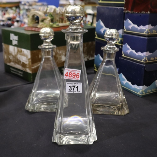 371 - Set of three crystal decanters in triangular form with silver plated tops, largest H: 33 cm. Not ava... 