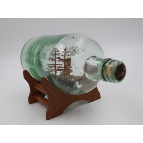 286 - Ship in a glass bottle on a wooden display stand, length 24cm. UK P&P Group 2 (£20+VAT for the first... 