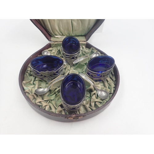 116 - Cased set of four white metal Art Nouveau open salts and spoons with original blue glass liners. UK ... 