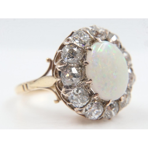 13 - 18ct gold cocktail ring, set with a large cabochon opal, surrounded by twelve old-cut diamonds total... 