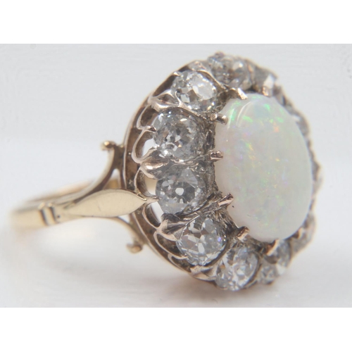 13 - 18ct gold cocktail ring, set with a large cabochon opal, surrounded by twelve old-cut diamonds total... 