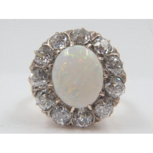 13 - 18ct gold cocktail ring, set with a large cabochon opal, surrounded by twelve old-cut diamonds total... 