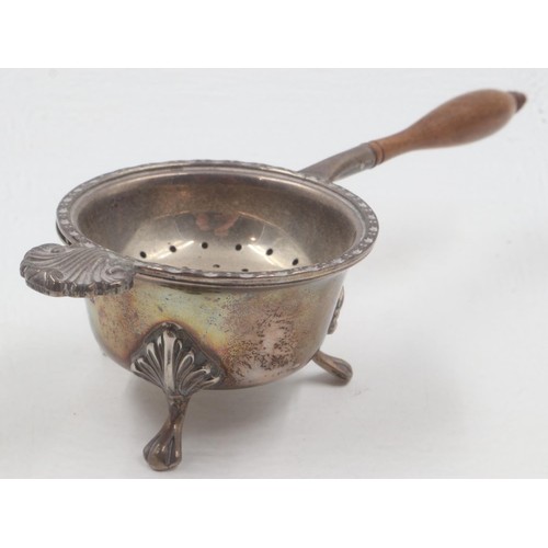 59 - Hallmarked silver tea strainer with turned walnut handle, with associated bowl rest, overall 99g. UK... 