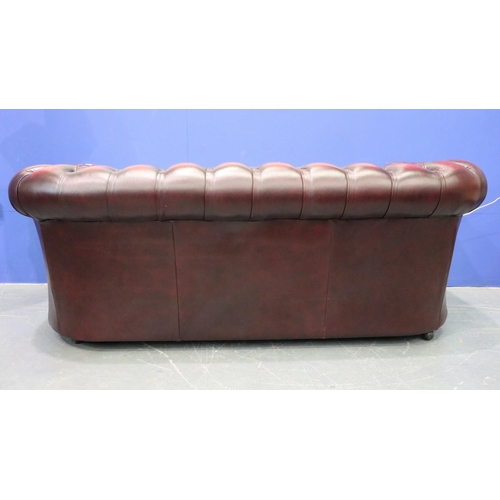 2042 - A modern Chesterfield three-seat sofa in ox-blood red leather. Not available for in-house P&P