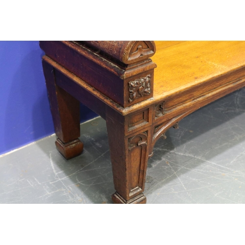 2044 - An early 19th century carved oak settle or window seat, decorated in the Gothic manner, with straw-f... 