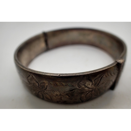 1049 - Hallmarked silver hinged bangle with unusual deployment clasp and chased decoration, 34g. UK P&P Gro... 