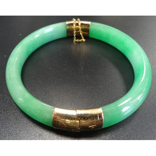 55 - HINGED GREEN JADE BANGLE
with fourteen carat gold mounts and safety chain