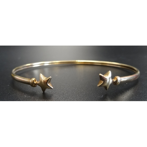 61 - NINE CARAT GOLD BANGLE
with star finials, approximately 2.7 grams