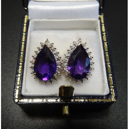 65 - PAIR OF AMETHYST AND DIAMOND CLUSTER EARRINGS
the central pear cut amethyst on each in illusion surr... 