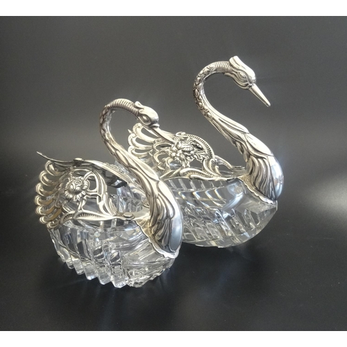 181 - TWO GRADUATED SILVER MOUNTED CUT GLASS TABLE SALTS
in the form of swans with articulated pierced sil... 