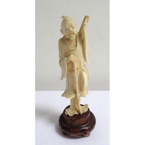 259 - CHINESE CARVED IVORY FIGURE
of an old man resting on his staff with his leg raised, 13cm high, on a ... 