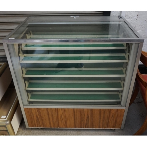 519 - TEAK AND CHROME FRAMED GLAZED REVOLVING DISPLAY CABINET
with various drawers, raised on wheels, 97cm... 