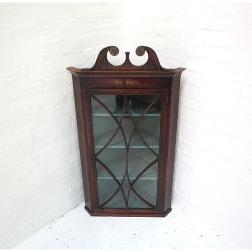 426 - GEORGE III MAHOGANY CORNER CABINET
with a scroll shaped pediment above a beaded glazed door, with a ... 