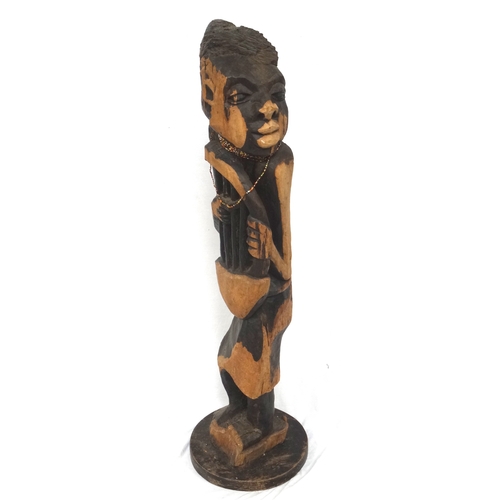 281 - CARVED WEST AFRICAN FIGURE OF A MUSICIAN
or story teller, playing a Bolon, raised on a shaped base, ... 