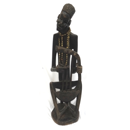 62 - SIGNED CARVED AFRICAN WOODEN FIGURE
of a story teller playing a three string Bolon seated on a stool... 
