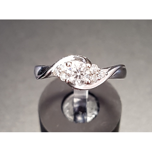 66 - PRETTY TWIST SET DIAMOND RING
the central round brilliant cut diamond flanked by three small diamond... 