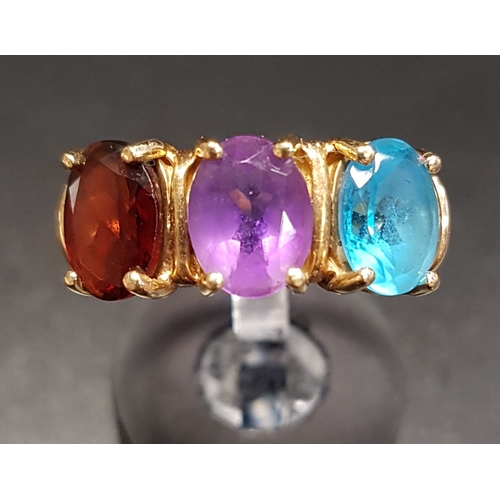 116 - BLUE TOPAZ, AMETHYST AND GARNET THREE STONE RING
the three oval cut gemstones on ten carat gold shan... 