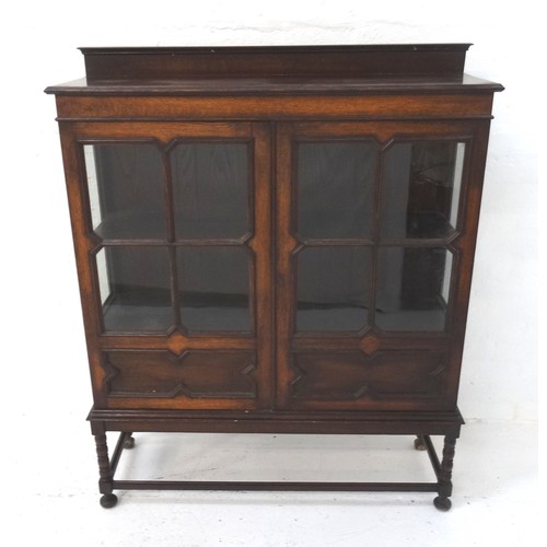 494 - OAK DISPLAY CABINET
with a raised back above a moulded top with a pair of panelled glazed doors belo... 