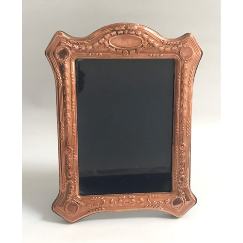 264 - EDWARDIAN STYLE COPPER PHOTOGRAPH FRAME
the shaped frame with relief floral decoration, on easel sup... 