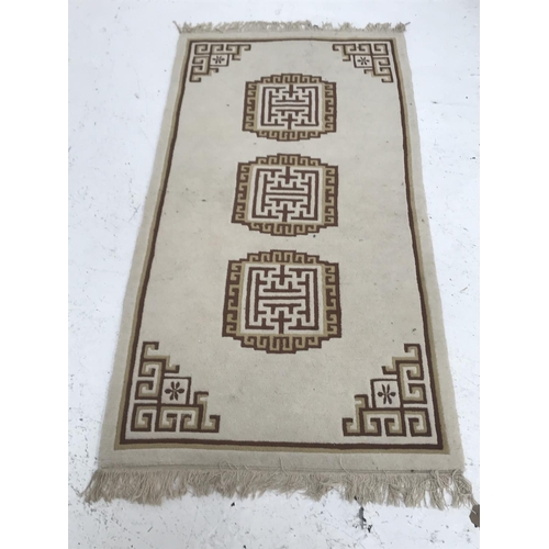418 - WOOL RUG
with a cream ground and three geometric motifs encased by a cream and brown border, fringed... 