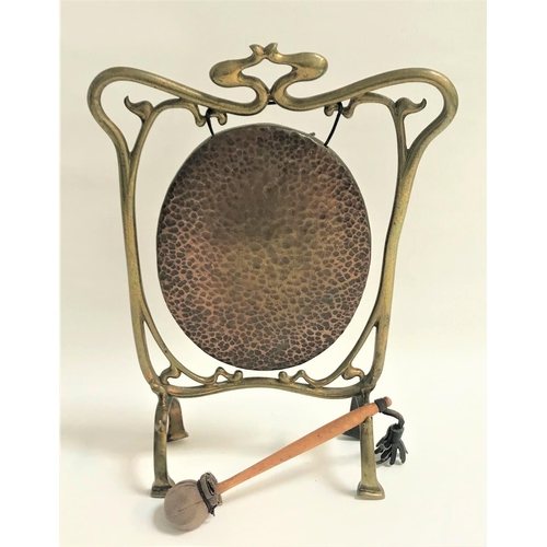 180 - ART NOUVEAU BRASS TABLE GONG
of shaped outline with an oval hammered gong, and a suede covered strik... 