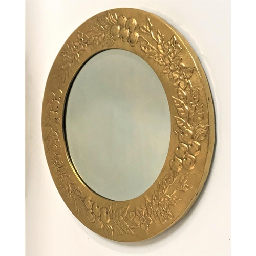 373 - CIRCULAR WALL MIRROR 
with a brass embossed frame decorated with flowers and fruit around a beveled ... 