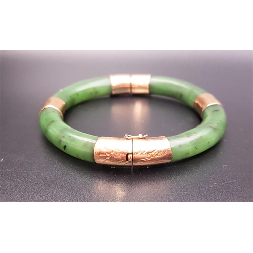 89 - FOURTEEN CARAT GOLD MOUNTED HINGED JADE BANGLE
the gold mounts with engraved decoration, with safety... 