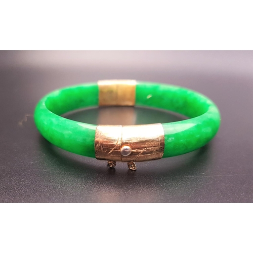 91 - FOURTEEN CARAT GOLD MOUNTED HINGED JADE BANGLE
the gold mounts with textured detail, with safety cha... 