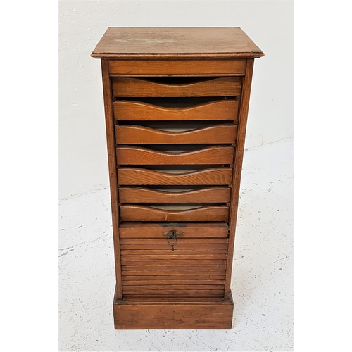 764 - OAK TAMBOUR FRONT MUSIC CABINET
with a drop down door revealing nine drawers, standing on a plinth b... 