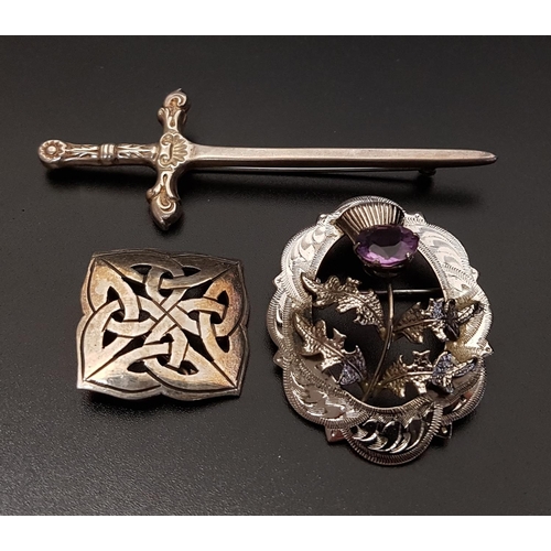 134 - TWO SCOTTISH SILVER BROOCHES AND A KILT PIN
comprising a an amethyst set thistle design brooch; anot... 
