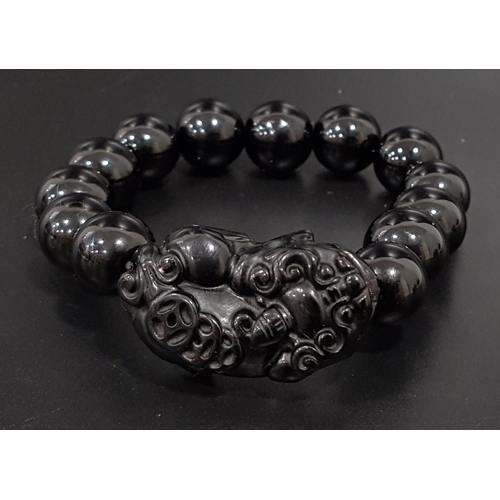 103 - ONYX BEAD BRACELET
comprising of thirteen circular beads and one carved dog of foe