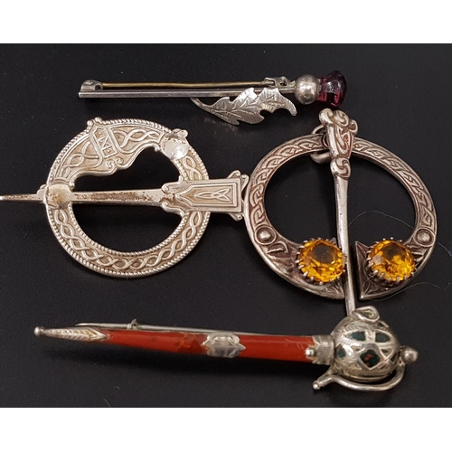 107 - FOUR SILVER SCOTTISH DESIGN BROOCHES
comprising an amber coloured glass set plaid brooch; another Ce... 