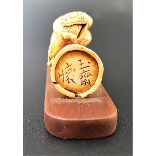 334 - JAPANESE IVORY NETSUKE
depicting a snake atop a section of bamboo eating a mouse, with signature to ... 