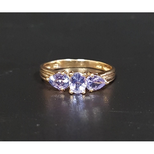 99 - TANZANITE THREE STONE RING
the central oval cut stone flanked by pear cut stones to each side, on fo... 