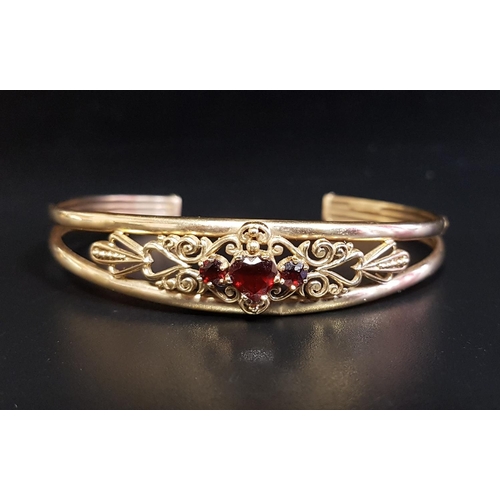 140 - GARNET SET NINE CARAT GOLD BANGLE
the three central garnets within decorative pierced scroll decorat... 